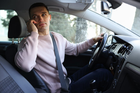 Driver talking on smartphone while driving modern car