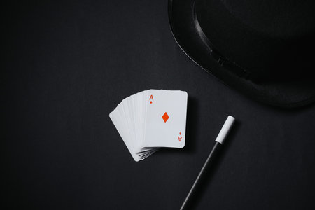Playing cards, hat and magic wand on black background, top viewの写真素材