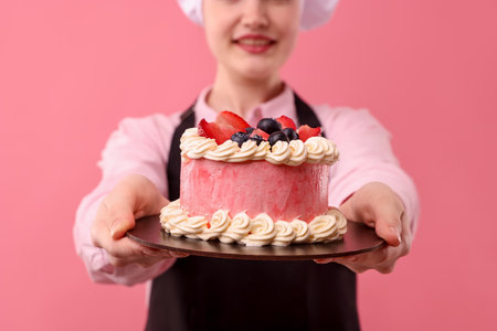 Confectioner holding delicious cake on pink background, closeupの写真素材