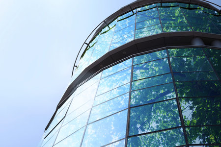Modern skyscraper and lush tree against blue sky, double exposure. Low angle view
