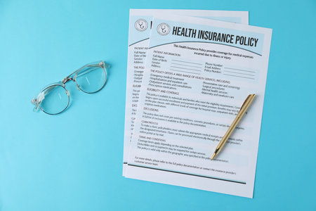 Health insurance policy forms, glasses and pen on light blue background, flat layの写真素材
