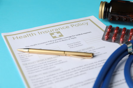 Health insurance policy, pen and pills on light blue background, closeupの写真素材