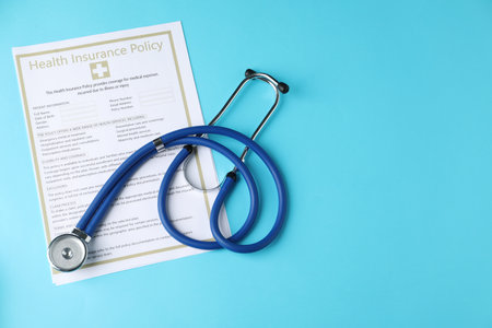Health insurance policy and stethoscope on light blue background, top view. Space for textの写真素材