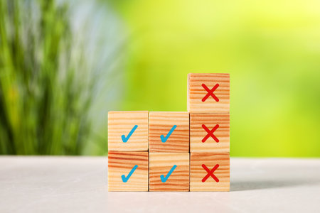 Wooden cubes with check and cross marks on tableの写真素材