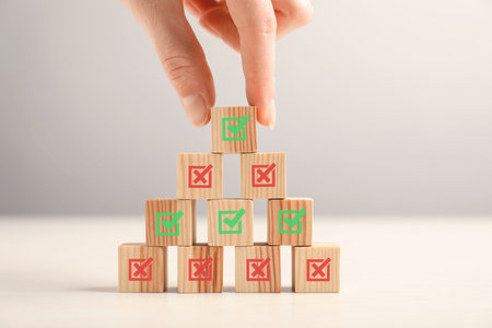 Approved. Woman choosing cube with check mark among other ones at table, closeupの写真素材