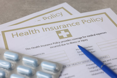Health insurance policy forms, pills and pen on grey table, closeupの写真素材