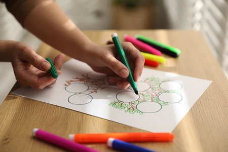 Woman drawing family tree at wooden table, closeupの写真素材