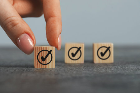 Approved. Woman touching cube with check mark on grey table, closeupの写真素材