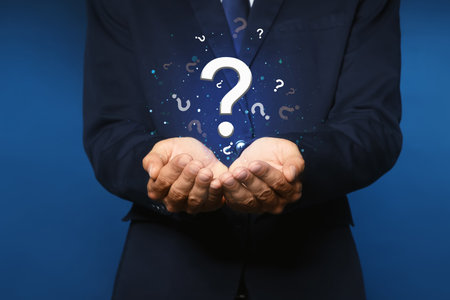 Businessman holding virtual question marks on dark blue background, closeupの写真素材