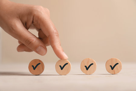 Woman touching wooden circle with check mark on beige background, closeupの写真素材