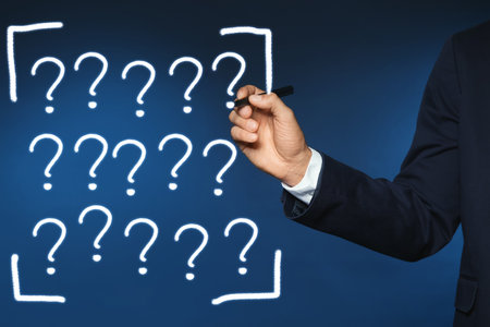 Businessman writing question mark on virtual screen against dark blue background, closeupの写真素材