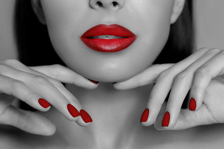Young woman with beautiful red lips and nail polish, closeup. Black and white effect with color accentの写真素材