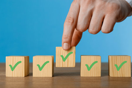 Approved. Man taking cube with check mark on blue background, closeupの写真素材