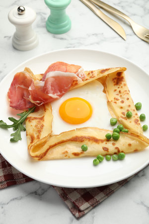 Delicious crepe with egg, bacon, arugula and green peas on white marble table, closeupの写真素材