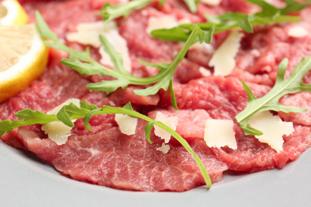 Fresh beef carpaccio with arugula, cheese and lemon on plate, closeupの写真素材