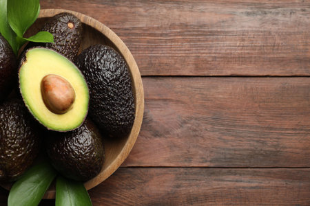 Fresh ripe avocados and leaves on wooden table, top view. Space for textの写真素材