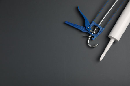Glue gun and tube on gray background, flat lay. Space for textの写真素材