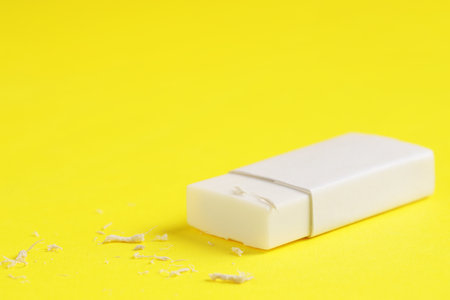 One eraser and scraps on yellow background, closeup. Space for textの写真素材