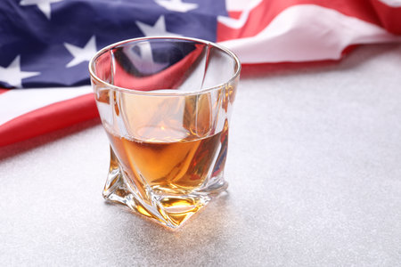 Glass of whiskey and American flag on light table, closeupの写真素材