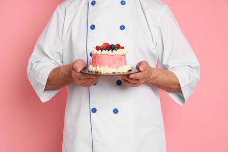 Professional pastry chef with delicious cake on pink background, closeupの写真素材