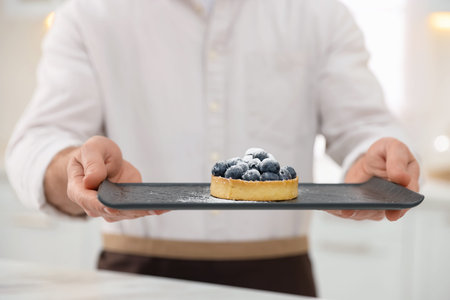 Confectioner with tart in kitchen, closeup