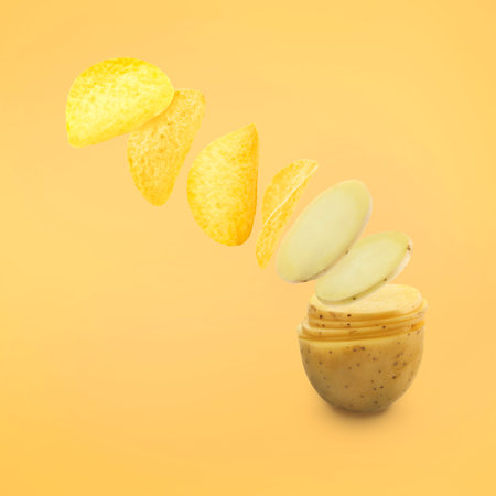 Raw potato slices transforming into crispy chips in air on pale orange backgroundの写真素材