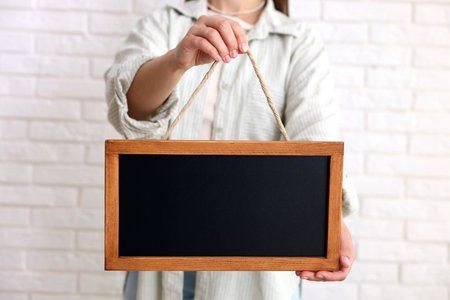 Woman holding blank small blackboard indoors, closeupの写真素材