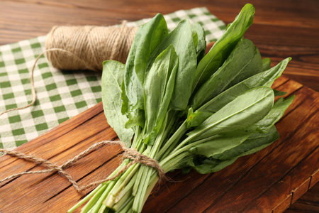 Bunch of fresh green sorrel leaves and twine on wooden table, closeupの写真素材