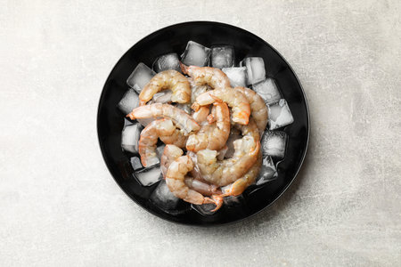 Fresh raw shrimps with ice cubes in bowl on grey table, top viewの写真素材