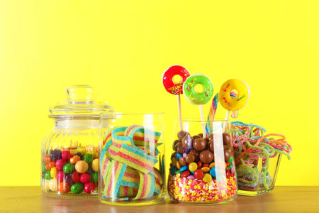 Candy bar. Many different sweets on wooden table against yellow backgroundの写真素材