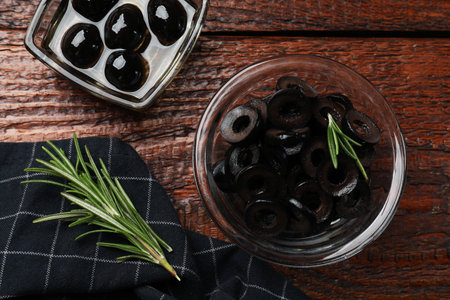 Delicious marinated olive rings and rosemary on wooden table, flat layの写真素材
