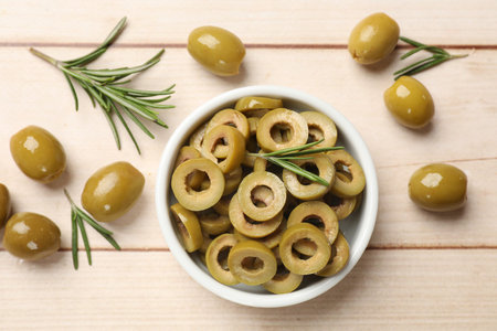 Delicious marinated olive rings, whole ones and rosemary on light wooden table, flat layの写真素材