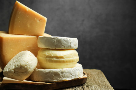 Different types of cheese on wooden table against grey background, closeup. Space for text
