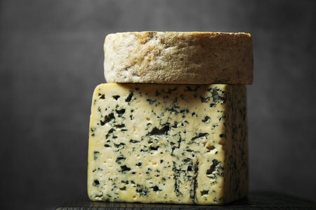 Fresh cheese on black wooden board against grey background, closeup