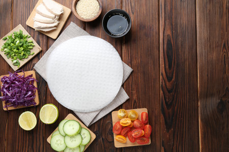 Edible rice paper sheets and ingredients on wooden table, flat lay. Space for textの写真素材