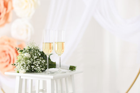 Glasses of champagne and wedding bouquet on table indoors, space for textの写真素材