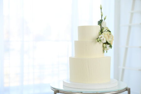 Delicious wedding cake with floral decor on table indoors, space for textの写真素材