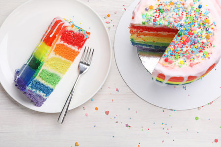 Delicious rainbow cake served on light wooden table, flat layの写真素材