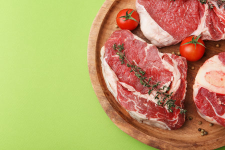 Pieces of raw beef, spices and tomatoes on green table, top view.の写真素材