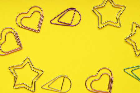 Frame of different paper clips on yellow background, flat lay. Space for textの写真素材