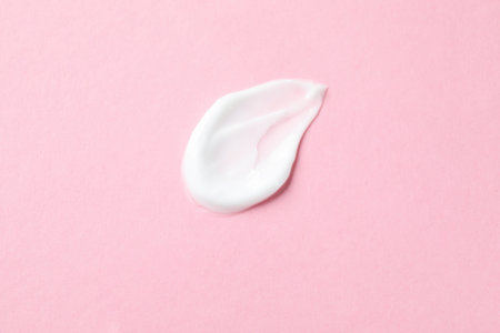 Sample of body cream on pink background, closeup