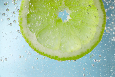 Soda water with lime slice against light blue background, closeupの写真素材