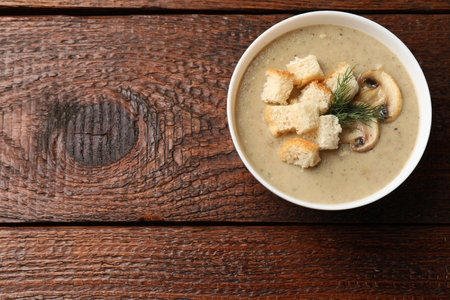 Delicious mushroom cream soup with croutons and dill on wooden table, top view. Space for textの写真素材