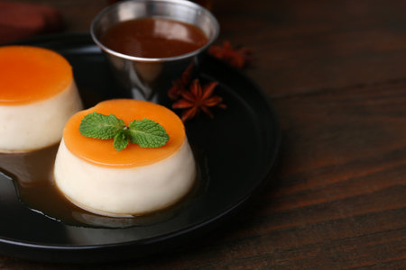 Tasty puddings with caramel sauce served on wooden table, closeup. Space for textの写真素材