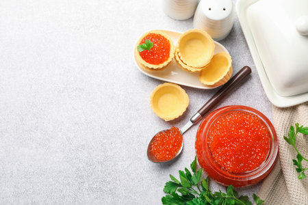 Delicious red caviar, parsley and tartlets on light table, flat lay. Space for textの写真素材