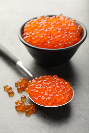 Tasty red caviar in bowl and spoon on grey table, closeupの写真素材