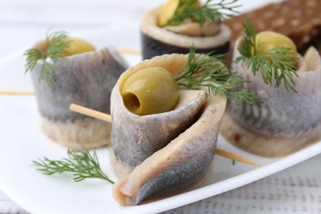 Delicious herring rolls with olives and dill on table, closeupの写真素材