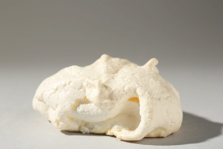 Delicious homemade meringue cookie on gray background, closeup