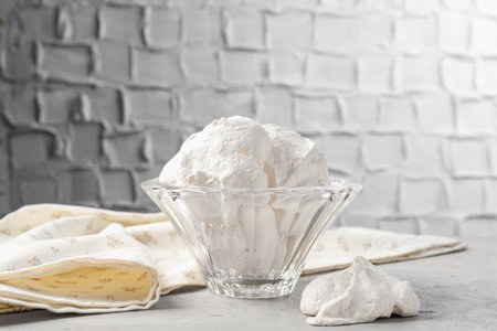 Delicious homemade meringue cookies in bowl on gray tableの写真素材