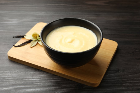 Vanilla pudding in bowl, flower on wooden board, closeupの写真素材